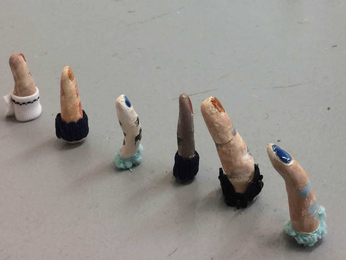 Sculptures of human fingers installed in an undulating line on the floor.