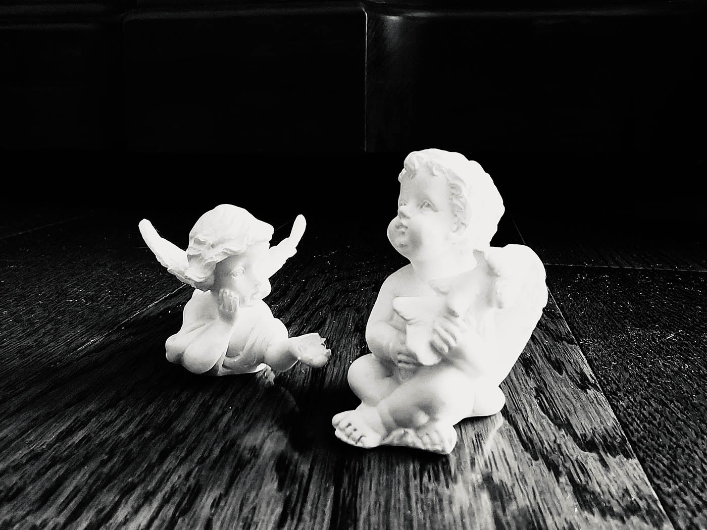 Black and white photo of two classical type sculptures of cherubs.