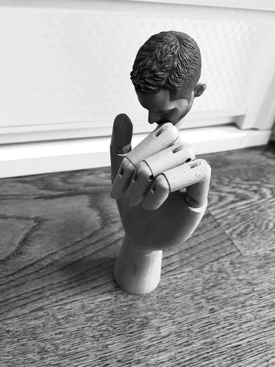 Black and white photo of hand holding sculpture of male head.