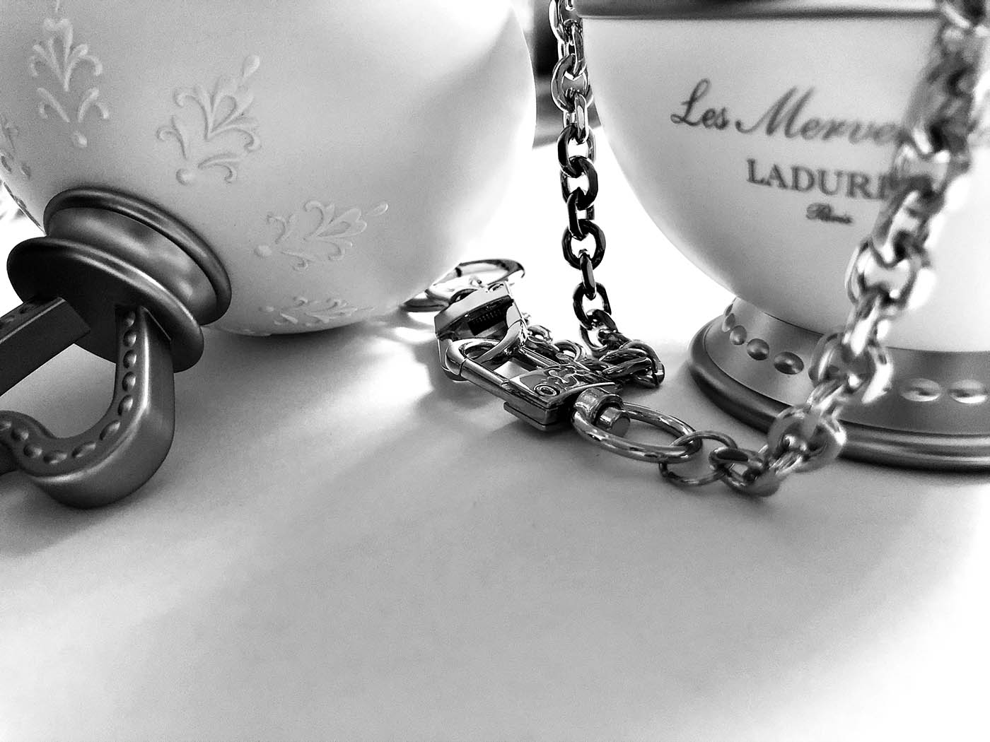 Black and white photo of tea cups depicted as ball and chains.