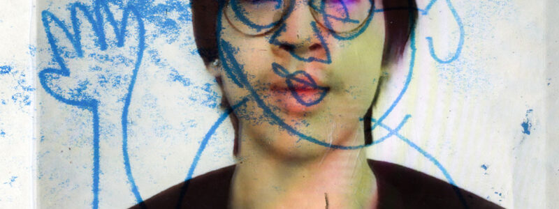 Portrait of the artist with doodles in blue ink over the image.